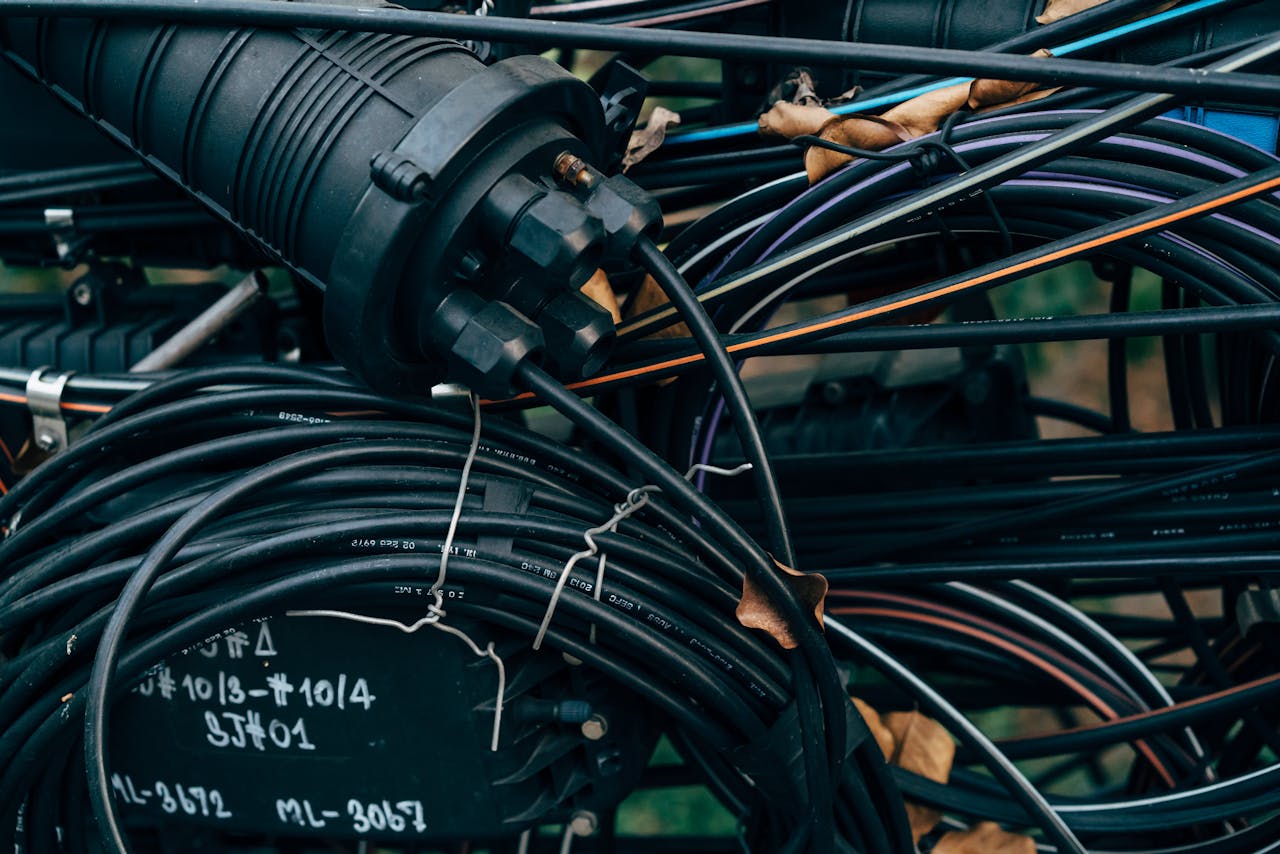 About Close-up view of intertwined black cables and connectors in an outdoor telecom setup.