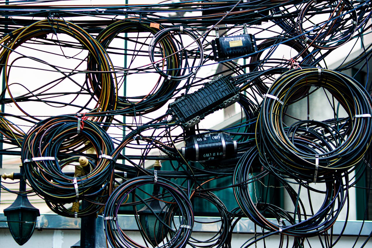 Services Intricate network of tangled power and communication cables outdoors.