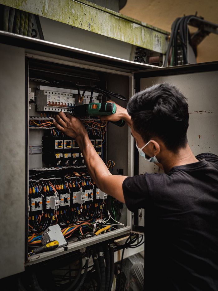 Crafting Captivating Headlines: Your awesome post title goes here Technician working on circuit breaker panel, adjusting electrical wires indoors.